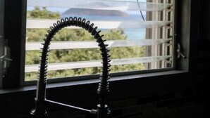 A kitchen with a window, a faucet, and a view of a mountain.