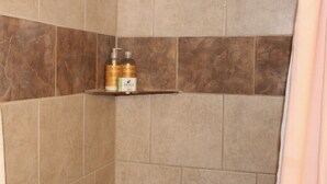 A bathroom with beige tiles and a shelf holding toiletries. - Cozy Chic Loft (Detroit)