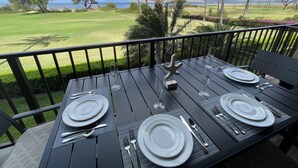 Een eettafel gedekt voor vier personen, met uitzicht op een golfbaan en palmbomen.