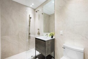 Une salle de bain moderne avec une douche à l’italienne, un lavabo sur pied et des toilettes.