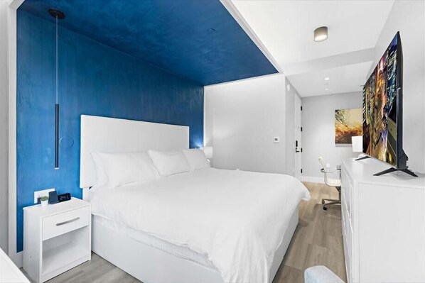 Une chambre moderne avec un grand lit, une table de chevet, un bureau et un téléviseur.