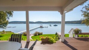 A covered deck with a view of a lake, boats, and a dock. - Glen Den Amazing Views of Sleeping Bear Dunes, Luxury Lakefront Home Glen Arbor (Empire)