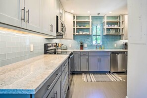 A modern kitchen with grey cabinets, a granite countertop, and a built-in dishwasher. - Relaxing Condo w/ Screened-In Lanai, 4 Mi to Beach (Naples)