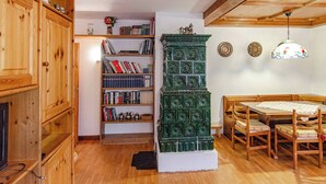 Zona pranzo in legno con tavolo e sedie, una libreria e un elemento decorativo verde.