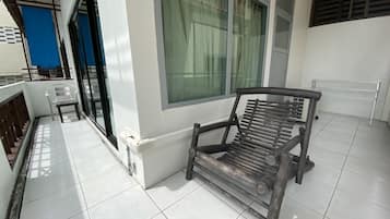 A balcony with a wooden bench, a window with curtains, and a blue door.