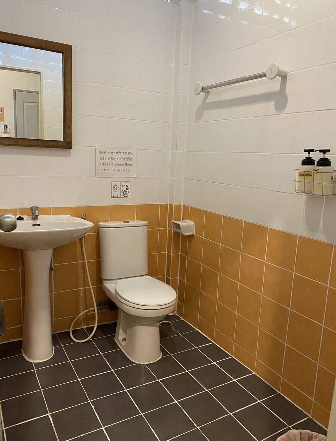 A bathroom with a sink, toilet, and hand sanitizer dispenser.