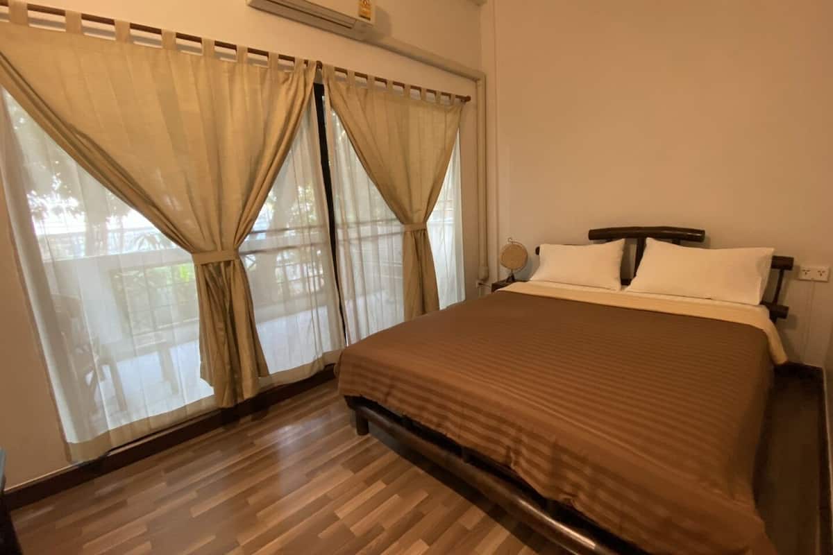 Ein Hotelzimmer mit einem großen Bett, Holzboden und einem Fenster mit Vorhängen.