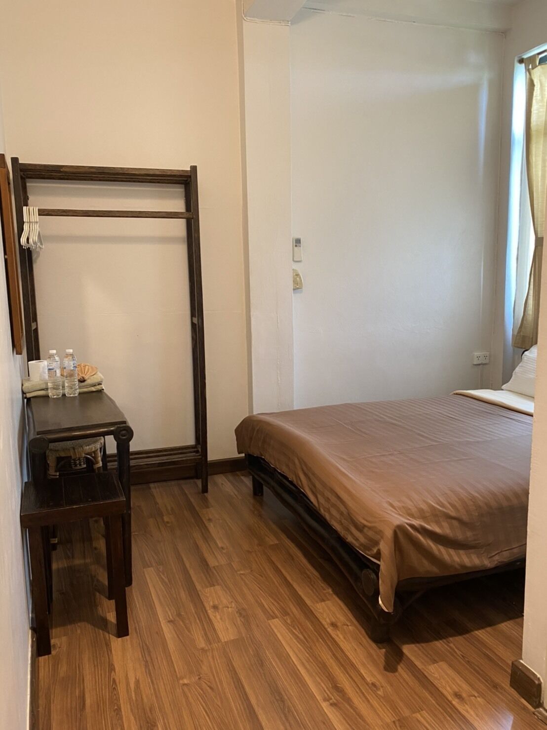 Ein Schlafzimmer mit einem hölzernen Bett, einem kleinen Tisch mit Flaschen und einem Spiegel.