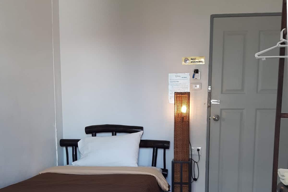 Ein Schlafzimmer mit Bett, Tür, Wandleuchte und einem Rauchverbot-Schild.
