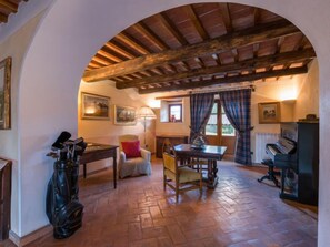 Experience the traditional charm of this inviting space, featuring a vaulted ceiling, dining area, piano, and artwork.