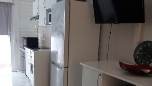 A compact kitchen with a refrigerator, microwave, and a flat-screen TV mounted on the wall. - big unit in the most beautiful residence in Guadeloupe (saint-françois)