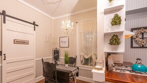 A dining area with a chandelier, a sign reading "Welcome", and a window with sheer curtains.