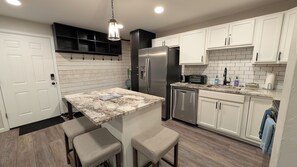 A modern kitchen with white cabinetry, a stainless steel refrigerator, a built-in oven, and a granite countertop. - Hot Spot Ski Condo Free Beaver Creek Shuttle (Avon)