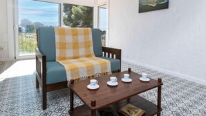 Une pièce avec un canapé bleu, une table en bois sur laquelle sont posées des tasses à thé, et un tableau accroché au mur.