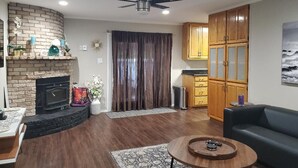 A living room with a fireplace, a ceiling fan, wooden cabinets, and a couch. - Charming Retreat  (San Antonio)