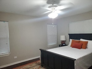 A bedroom with a bed, a nightstand, a lamp, and a ceiling fan.