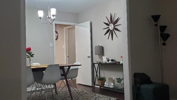A modern living room with a dining area, a chandelier, a decorative wall piece, and a floor lamp. - Charming Retreat  (San Antonio)