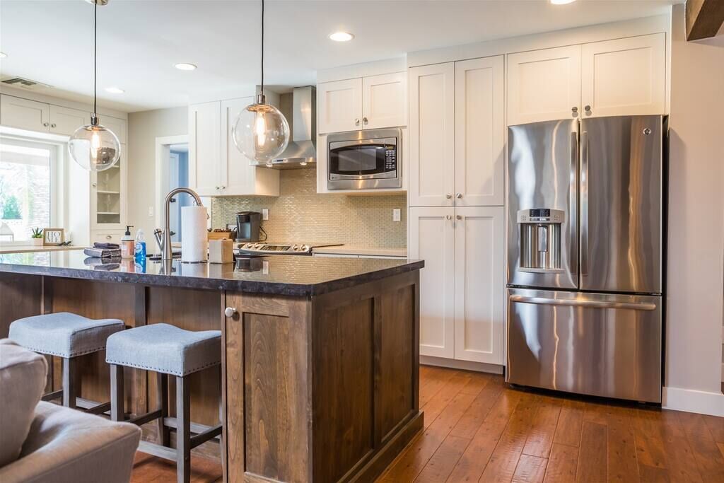 A modern kitchen with a central island, stainless steel appliances, and bar stools.