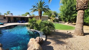 A swimming pool with lounge chairs and a building with a covered patio. - Kierland oasis, pool heater, spa, putting green (Scottsdale)