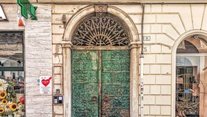 Une porte verte ornée d’une arche décorative, une enseigne avec un cœur et l’année 2025, et une vitrine où sont exposées des chaussures.