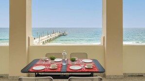 Une table dressée pour le dîner, avec vue sur l’océan et une jetée.