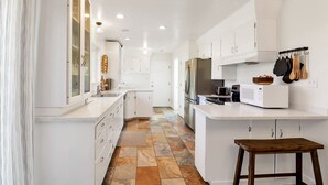 Una cocina moderna con armarios blancos, una isla central y un banco de madera.