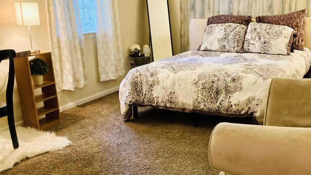 A bedroom with a large bed, a chair, a small table, and a mirror. - Get Away Sanctuary in Stone Mountain Mins from ATL (Stone Mountain)