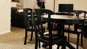 A dining area with a round table, four chairs, a television, and a coat rack. - Get Away Sanctuary in Stone Mountain Mins from ATL (Stone Mountain)