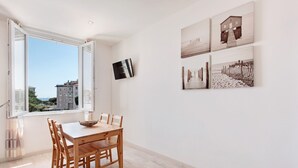 Een eethoek met een houten tafel en stoelen, een raam met vrij uitzicht en kunst aan de muur.