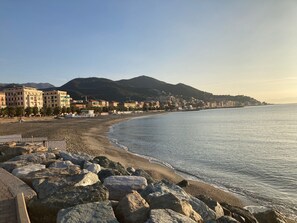 Eine Küstenstadt mit Strand, felsiger Uferlinie und Gebäuden im Hintergrund.