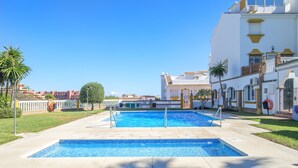 A swimming pool with a tiled deck, surrounded by a white building with yellow accents and a clear blue sky. - Holiday home "Balcon de Benalmadena Ocean Views" with Pool, Terrace & Wi-Fi [only guests over 25] (Benalmádena)