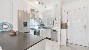 A modern kitchen with white cabinetry, a stainless steel refrigerator, a microwave, and a dishwasher. - Holiday home "Balcon de Benalmadena Ocean Views" with Pool, Terrace & Wi-Fi [only guests over 25] (Benalmádena)