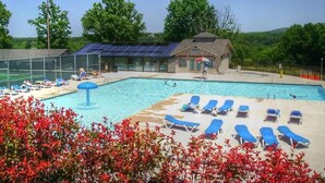 Ein Schwimmbecken mit Liegestühlen und ein Gebäude mit Solaranlagen.