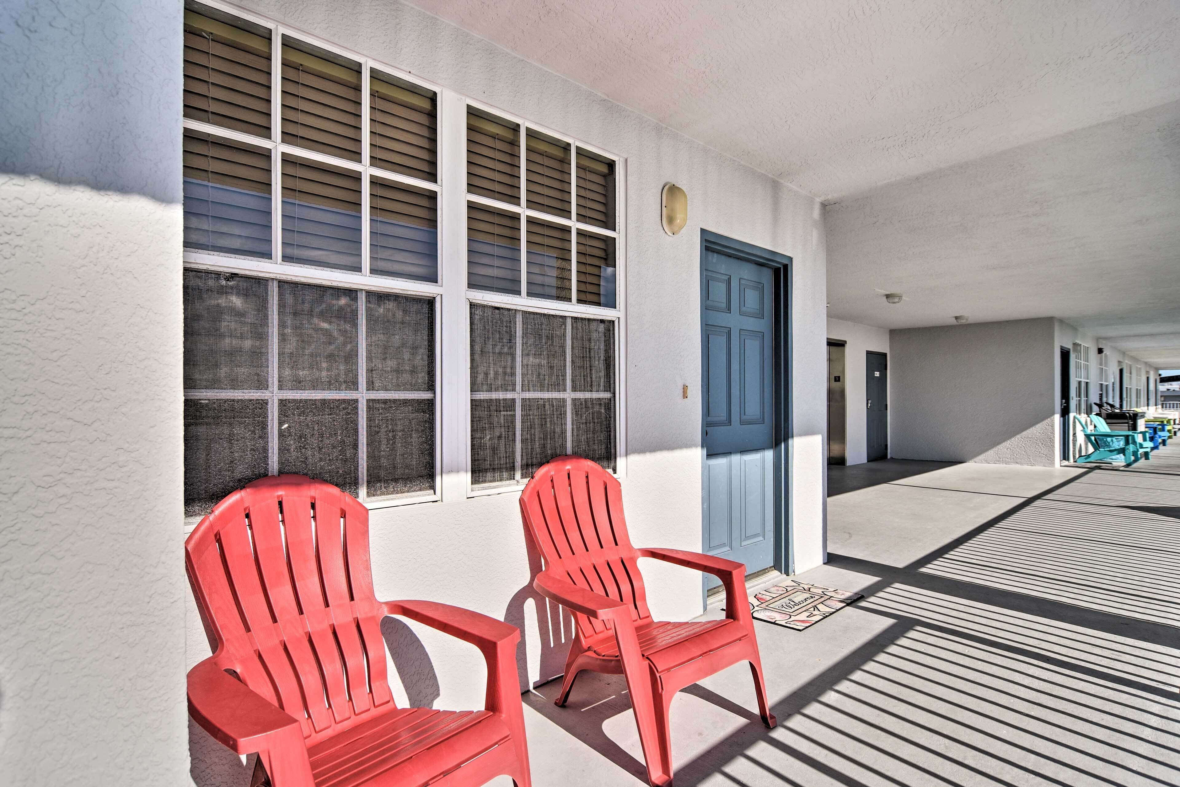 A building with a blue door, two red chairs outside, and a covered walkway.