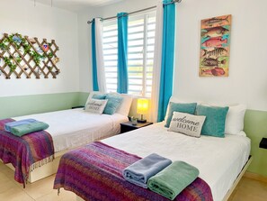 A hotel room with two beds, a window with curtains, a wall-mounted plant, and a fish-themed artwork. - Estudio with Bay views mins to Poblado de Boqueron & Heated Pool (3A) (Boquerón)