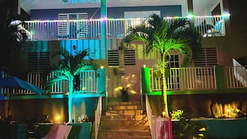 A two-story building with a balcony on the upper level, a staircase leading to the entrance, and outdoor seating areas.