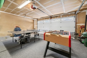 En garage med et bordtennisbord, et fodboldbord og en garageport.