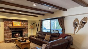 Uma sala de estar aconchegante com lareira de tijolos, sofá de couro e mesa de centro de madeira.