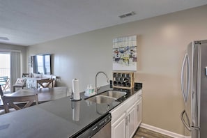 A modern kitchen with a central island, stainless steel appliances, and a dining area with a view. - Middle Bass Condo w/ Balcony, Lake Erie Views (Middle Bass)