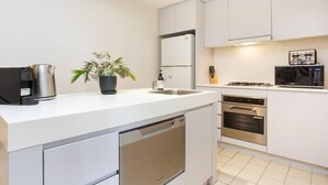 Une cuisine moderne avec des meubles blancs, un lave-vaisselle encastré, une cuisinière et un four à micro-ondes.