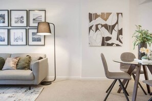 A modern living room with a sofa, a coffee table, a lamp, framed pictures, and a large abstract painting. - Heart of Darling Harbour,King St Wharf,Barangaroo (Sydney)