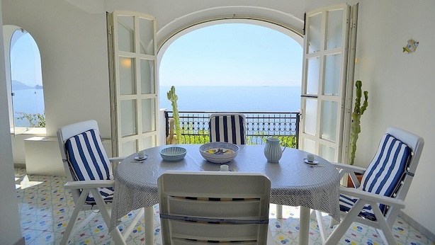 A dining area with a table and chairs, a view of the sea, and a balcony with a railing. - Casa Giasone: A characteristic and welcoming apartment that is part of a villa built sheer above the sea and with direct access to the sea, with Free WI-FI. (Praiano)
