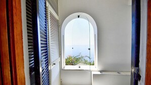 A narrow hallway with a window leading to a balcony, a white sink, and a tiled floor. - Casa Giasone: A characteristic and welcoming apartment that is part of a villa built sheer above the sea and with direct access to the sea, with Free WI-FI. (Praiano)