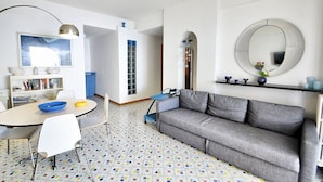 A modern living room with a grey sofa, a round mirror, a bookshelf, and a patterned floor. - Casa Giasone: A characteristic and welcoming apartment that is part of a villa built sheer above the sea and with direct access to the sea, with Free WI-FI. (Praiano)