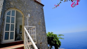 A stone building with a white door and steps leading to a balcony. - Casa Giasone: A characteristic and welcoming apartment that is part of a villa built sheer above the sea and with direct access to the sea, with Free WI-FI. (Praiano)