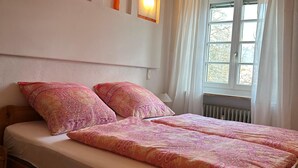 A double bed with patterned bedding, a wooden headboard, and two wall-mounted lights.