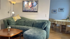A living room with a green sofa, a wooden coffee table, a lamp, and a painting on the wall.