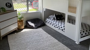 Habitación infantil con literas, cómoda, ventana con vistas y ventilador de techo.