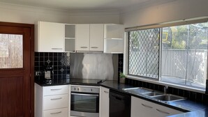 Cocina moderna con armarios blancos, encimera negra y pileta de acero inoxidable.