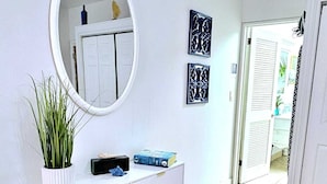 A hallway with a white dresser, a round mirror, and two wall-mounted decorative pieces.